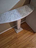 angled view of marble demi-lune top, pedestal and base