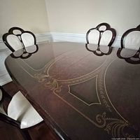 Table surface showing gold scroll detail and three chairs