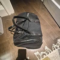 Overall view of black canvas duffel bag lying on floor