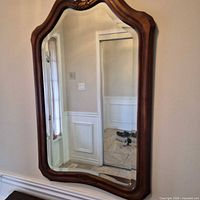 Full view of arched mahogany finish wall mirror mounted on wall