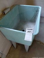 Overall view of aqua plastic freestanding sink in corner