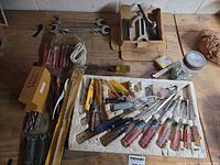 overview of assorted hand tools, drill bits, hardware on workbench