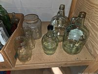 Shelf with large glass jugs and mason jars