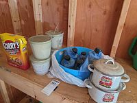 Overview showing enamel soup pots, stack of bucket candles and bowl of glass oil burners