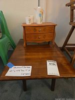 Low wooden table topped with small jewelry chest, pitcher and mugs