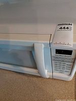 Front view of Hamilton Beach white microwave showing control panel, handle, and overall cosmetic condition