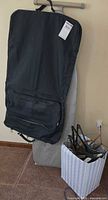 Ironing board standing upright with garment bag draped over and box of hangers