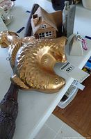 Group shot showing copper fish mold, wooden stick, ceramic house, hip flask, cowbell