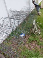Multiple rolled tomato cages/fencing, coiled garden hose, scarecrow
