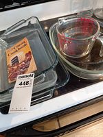 Stacked rectangular baking dishes with lot tag and cookbook for scale