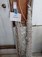 Full view of bundled rope hammock leaning against wall