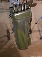 Green golf bag on push cart with visible clubs