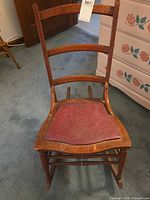 Front view of wooden ladderback rocking chair with red vinyl seat