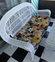White wicker loveseat with multicolor floral cushions