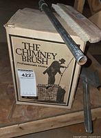 Box labeled THE CHIMNEY BRUSH with pole, brush head and scraper visible