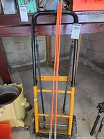 Front view of yellow/black hand truck with marker rods and straps visible