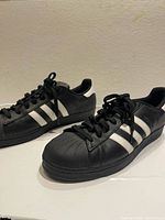 Side view of both shoes showing stripes, heel tab, shell toe