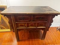 Front view showing drawers, scalloped apron, leg structure and remaining red lacquer