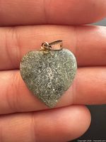Front view of jade heart pendant on fingers