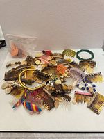 Wide view of assorted combs, clips, holders, green ring, bagged pink barrettes