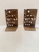 front view of both brass bookends showing cut-out cityscape side