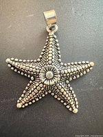 front view of sterling silver starfish pendant displaying dotted texture and central stone