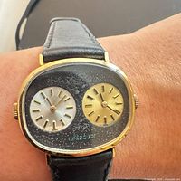 Front view on wrist showing dual sub-dials, gold-plated case, leather strap
