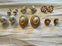All five pairs of vintage gold-tone faux pearl earrings displayed together