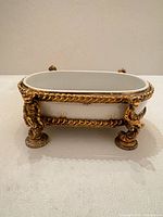 Side view showing porcelain basin and ornate gilt metal frame with figural supports