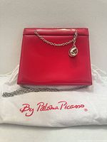 Front view of red patent leather bag on dustbag