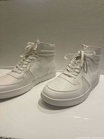 Side view of both white high-top sneakers