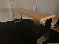 Side view showing full bench profile, wood top and one stainless leg