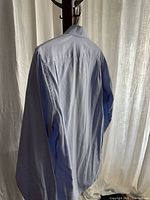 Back view of light blue shirt hanging, shows overall condition and fabric