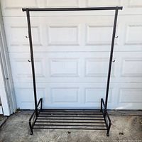 Full view of black metal clothing rack in front of garage door