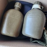 Two plastic military canteens inside box