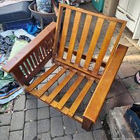 Angled view of oak futon frame showing slatted back, seat and one arm