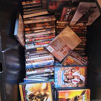 Bin filled with stacked DVD and Blu-ray cases; titles such as S.W.A.T., Radio visible