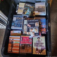 Top-down view of tote showing mixed DVDs/Blu-rays including Tron: Legacy, Parkland, Borat, Juno, The River Niger