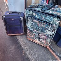 Blue and tapestry rolling suitcases side by side showing fronts