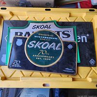 Overlapped view showing Skoal circular 70th Anniversary sign atop Skoal Bandits sign