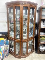 Full view of wood corner display cabinet filled with dinnerware