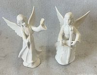 Front view showing both Dresden porcelain angel figurines, one with cymbals one with cello
