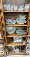 Cabinet view showing multiple shelves of clear crystal bowls, plates and glasses
