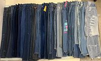 Full lot of 31 women’s jeans lined upright showing variety of washes and styles