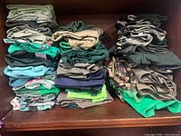 Stacks of folded green shirts on shelf