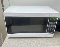 Front view of white digital countertop microwave showing door, keypad, display