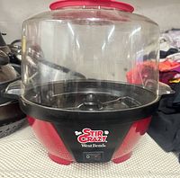Front view of red West Bend Stir Crazy popcorn popper showing clear lid and control switch