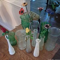 All twelve vases grouped on table with several artificial flowers inserted