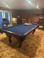 overall view of pool table in room with cue stand and chair visible