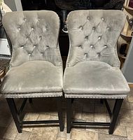 Two gray tufted bar stools front view showing design and legs